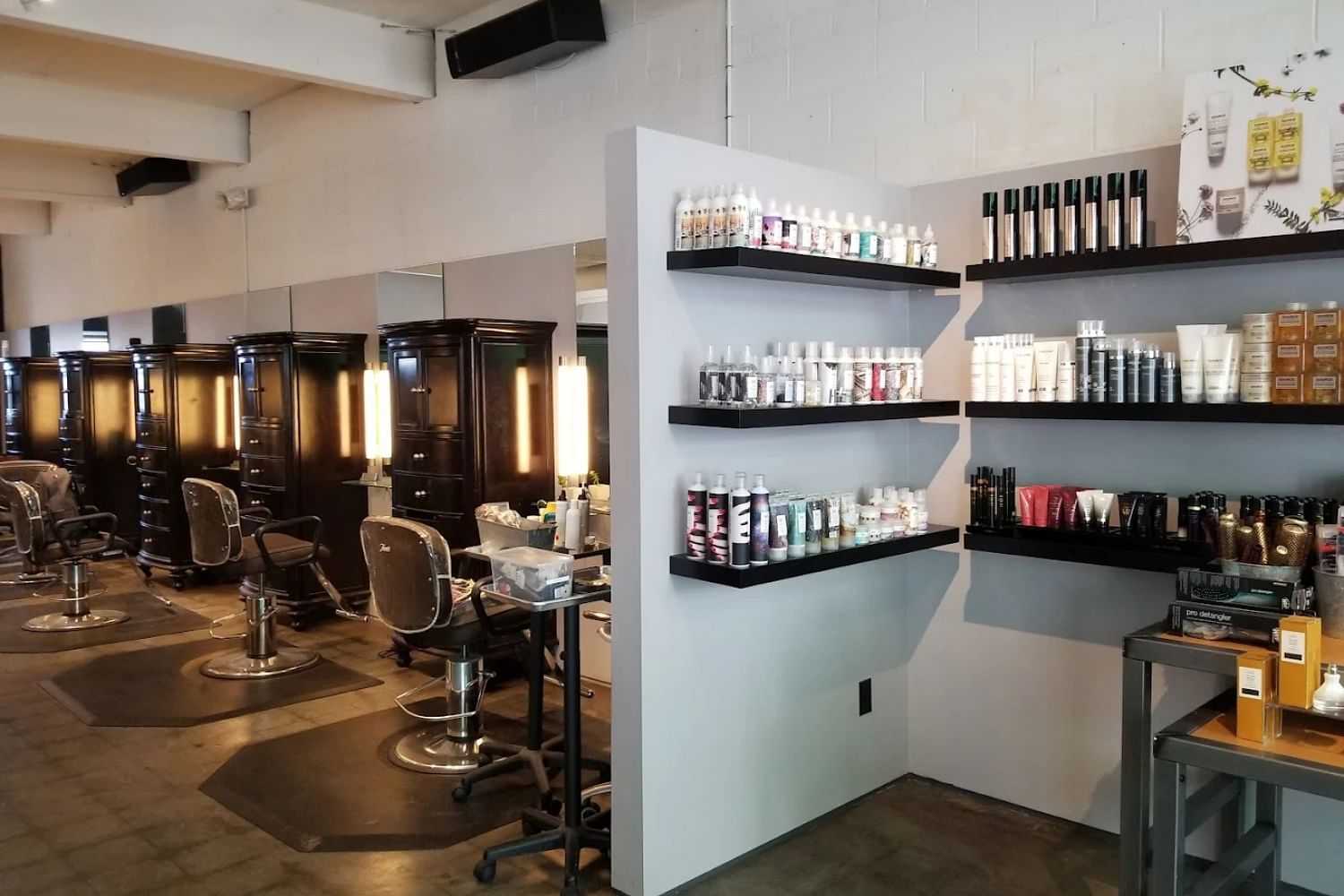 Modern salon interior with styling chairs, mirrors, and shelves of hair products.