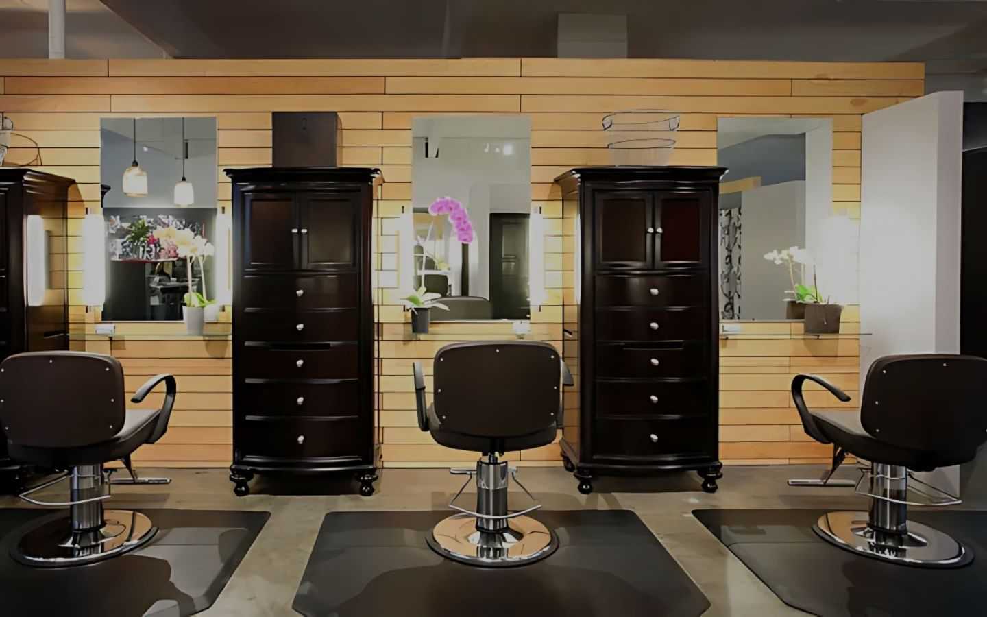 Modern hair salon with three styling stations and elegant black chairs.